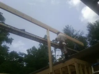 Carpenter setting a ridge beam over a new addition frame — Ice Dam Removal by Roofing Brothers in Donalds