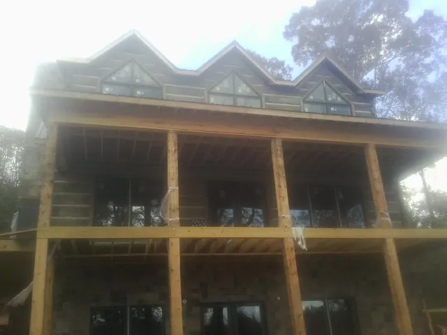 Dormers and porch framing on a large log home under construction — Roof Coating work by our crew in Donalds