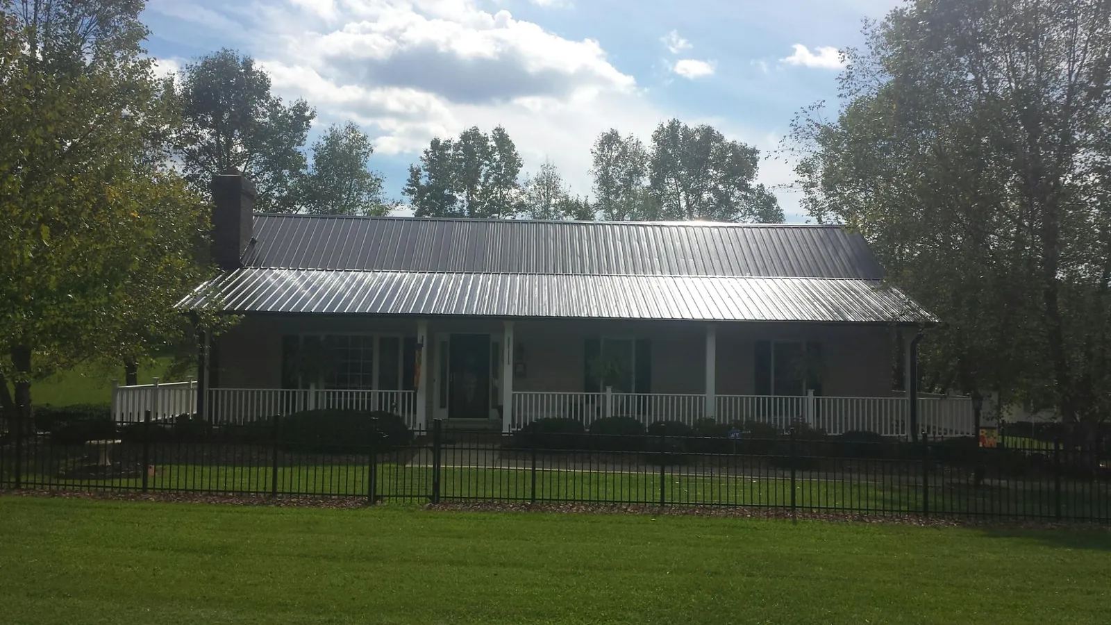 Gray metal roof on a brick ranch with a full width front porch — Gutter Guard Installation work by our crew in Donalds