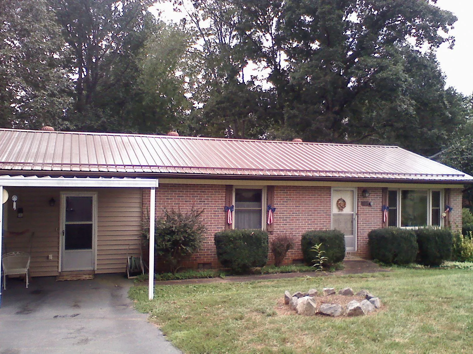 Bronze metal roof and carport on a brick ranch home — Roof Repair work by our crew in Donalds