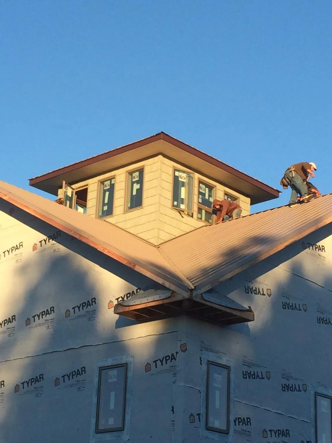 Roofers working around a rooftop cupola on a new metal roof at sunset — Roof Waterproofing in Donalds by Roofing Brothers